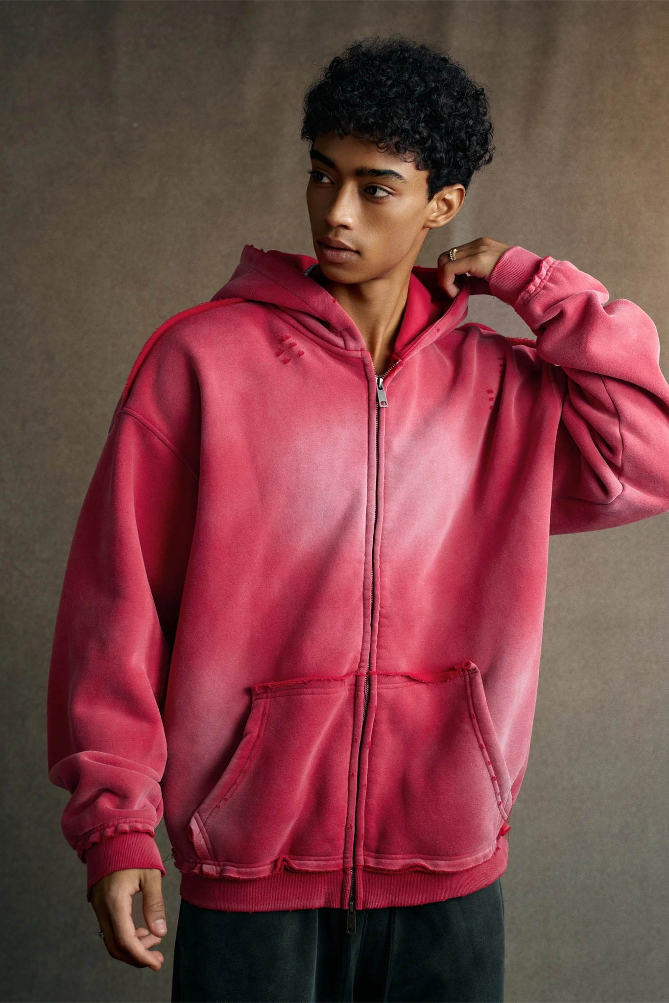 Person wearing a pink hoodie against a brown background
