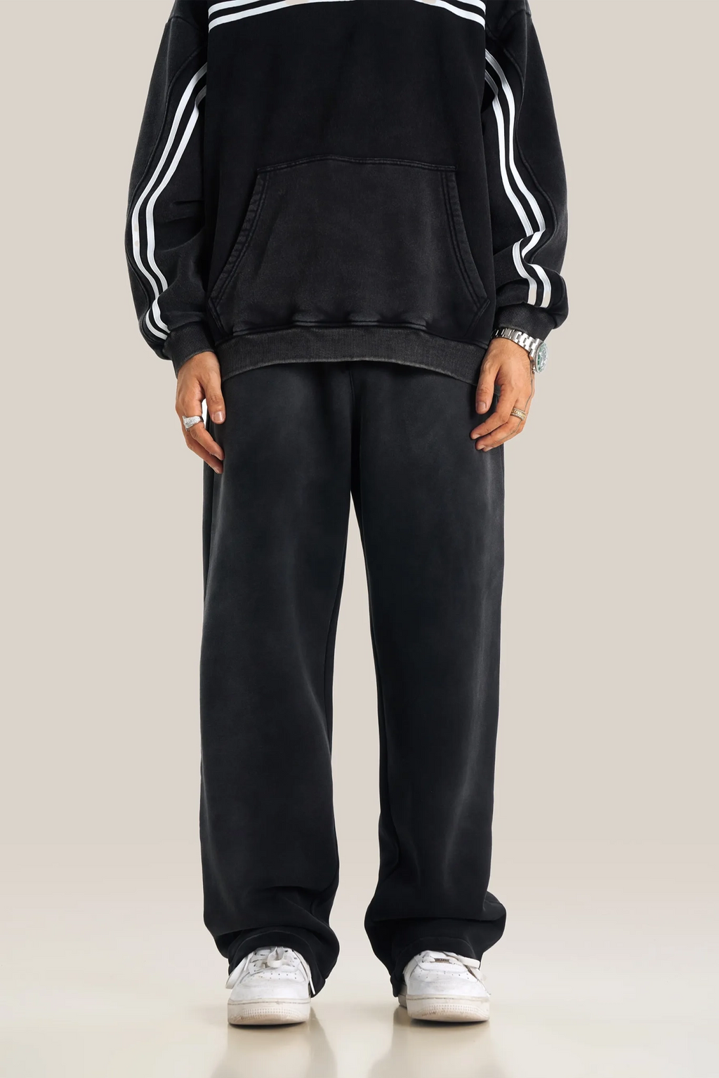 Person wearing a black tracksuit with white stripes on a beige background