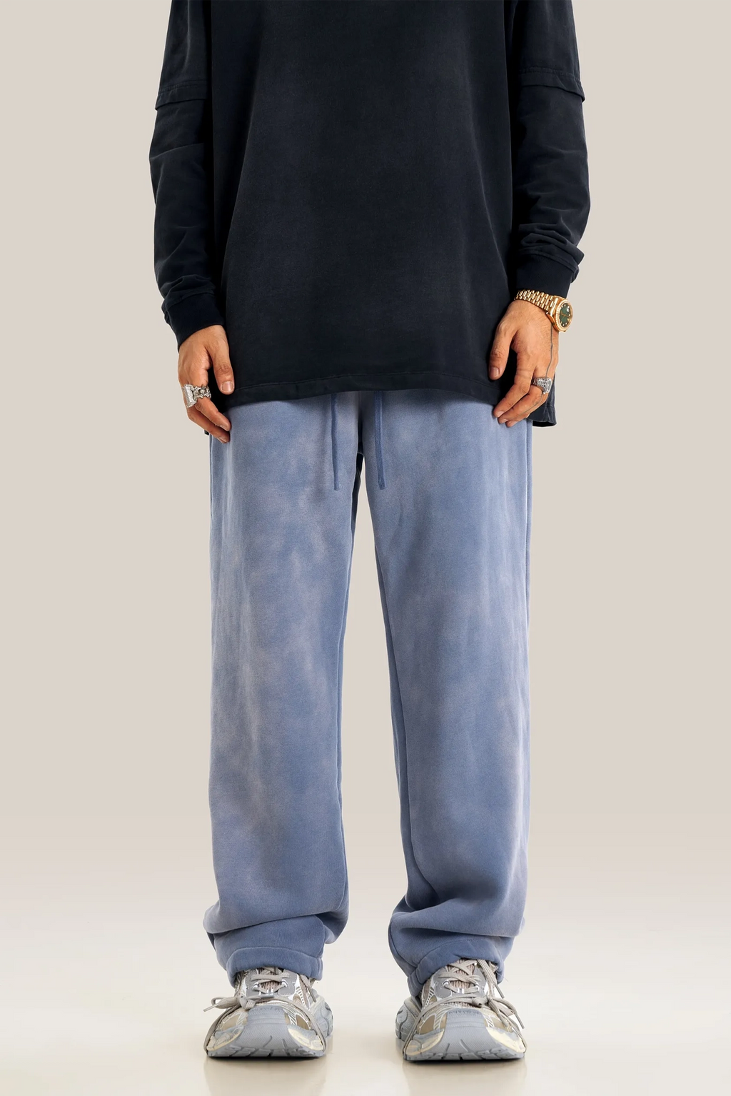 Person wearing a black oversized sweatshirt and light blue jeans on a plain background