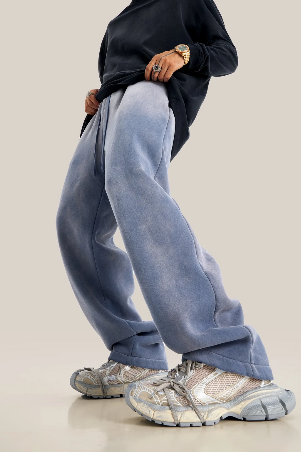 Person wearing blue pants and gray sneakers on a beige background