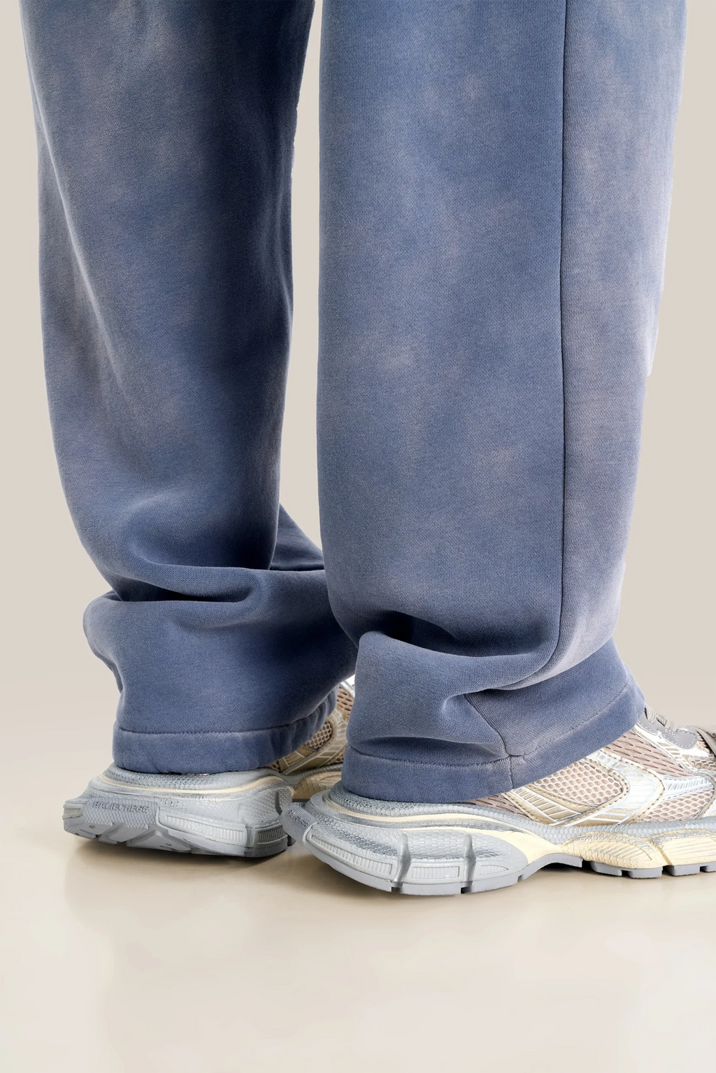Blue sweatpants worn by a person on a beige background