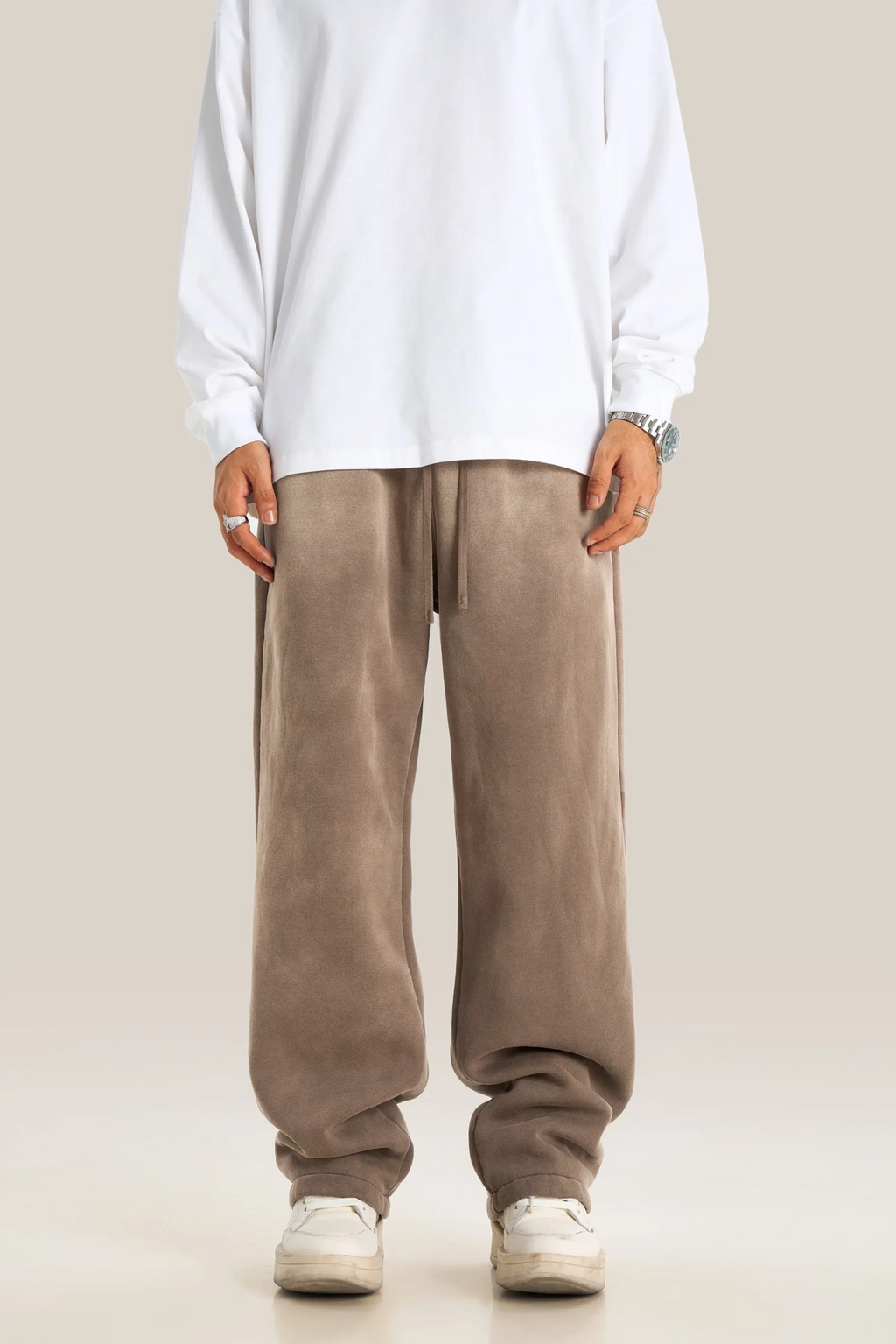 Person wearing a white shirt and brown pants on a plain background