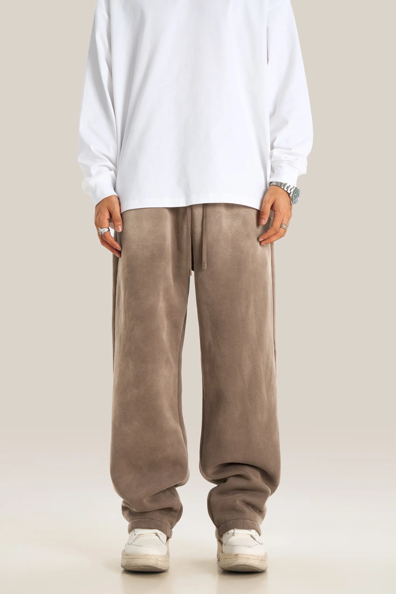 Person wearing a white shirt and brown pants on a plain background