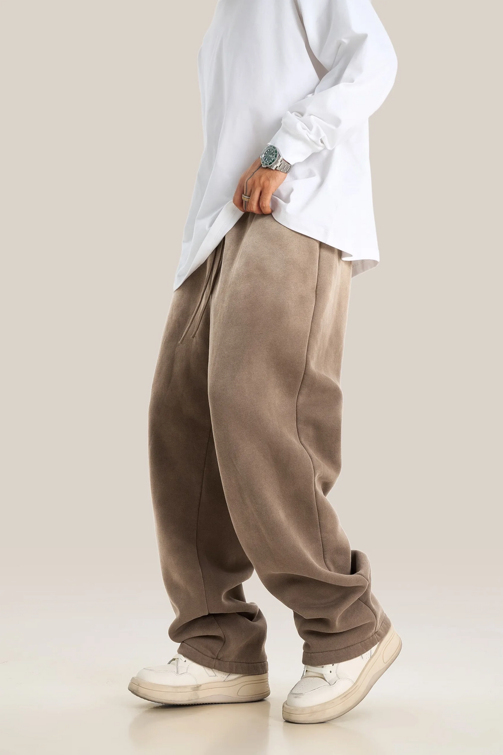 Person wearing a white shirt and beige pants on a plain background