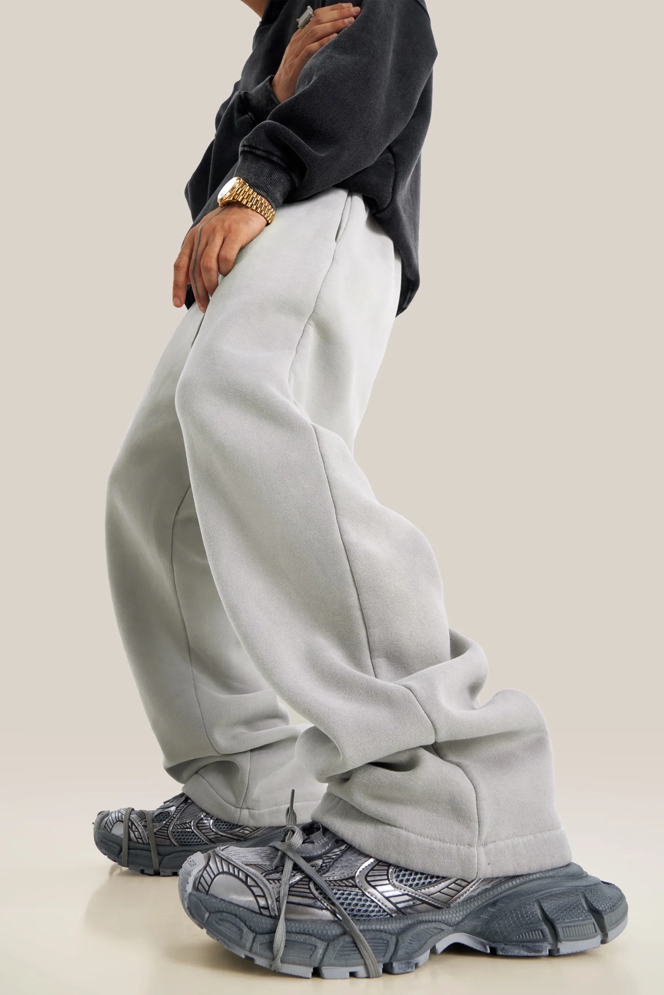 Person wearing light gray sweatpants and gray sneakers on a plain background