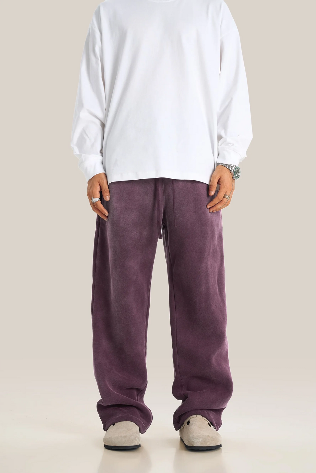 Person wearing a white shirt and purple pants on a plain background