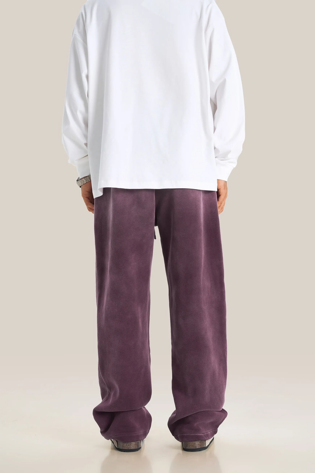 Person wearing a white shirt and purple pants on a beige background