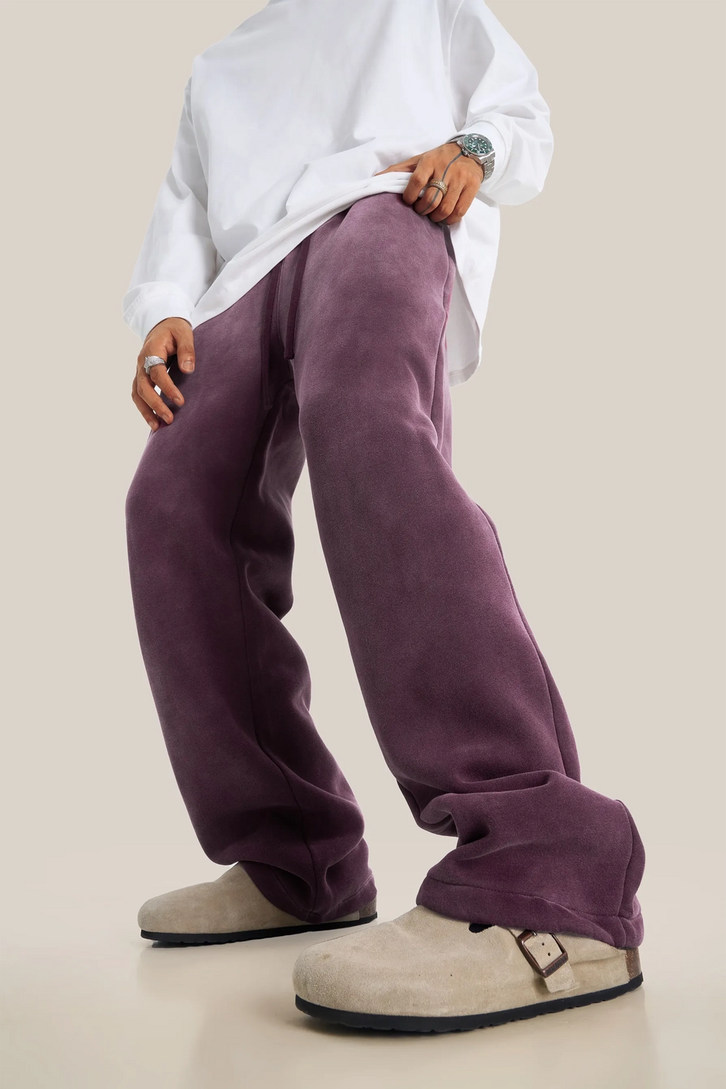 Person wearing a white shirt and purple pants on a beige background