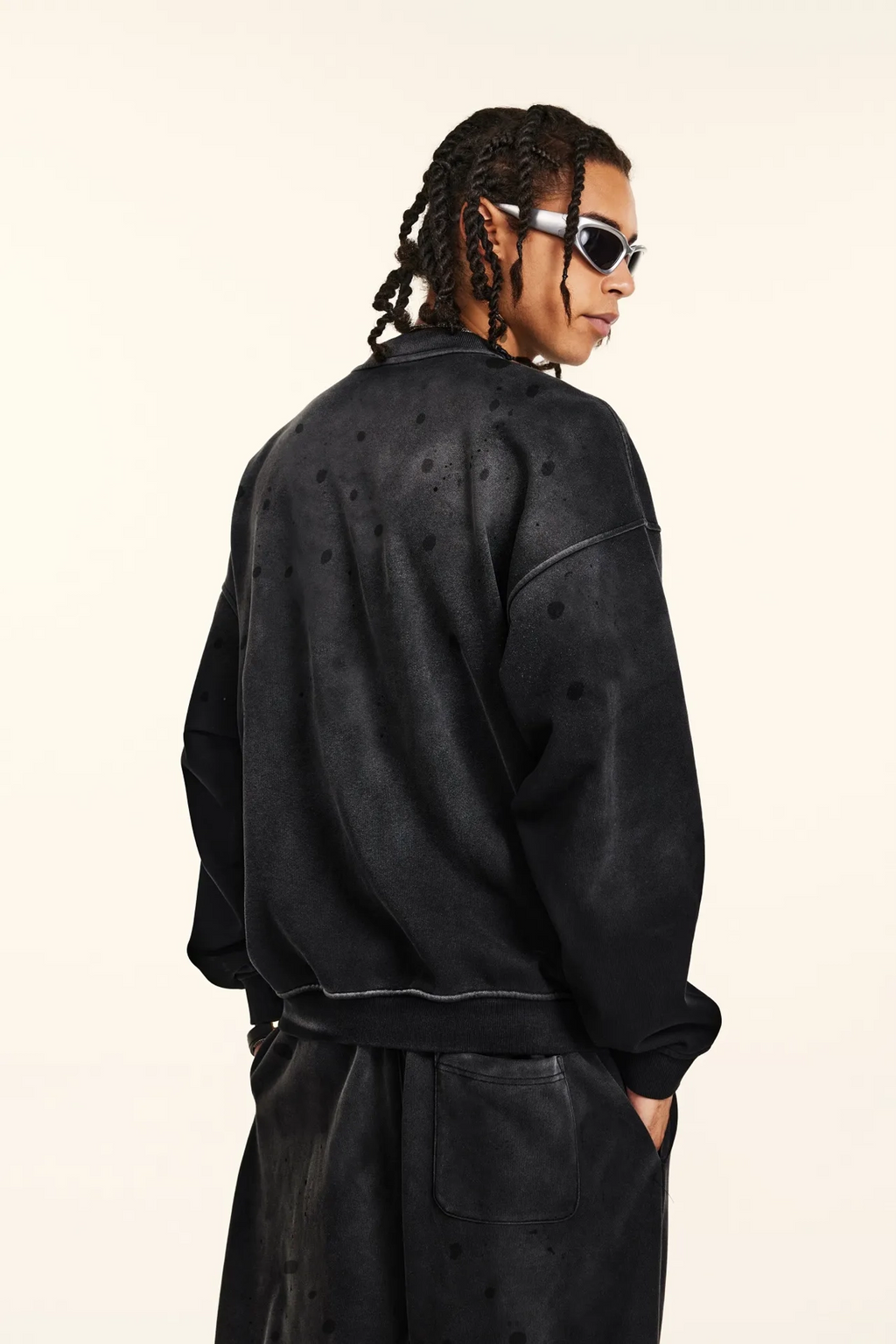 Person wearing a black jacket and pants on a beige background