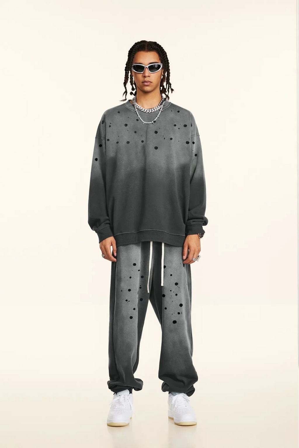 Person wearing a gray sweatshirt and pants with black polka dots on a beige background