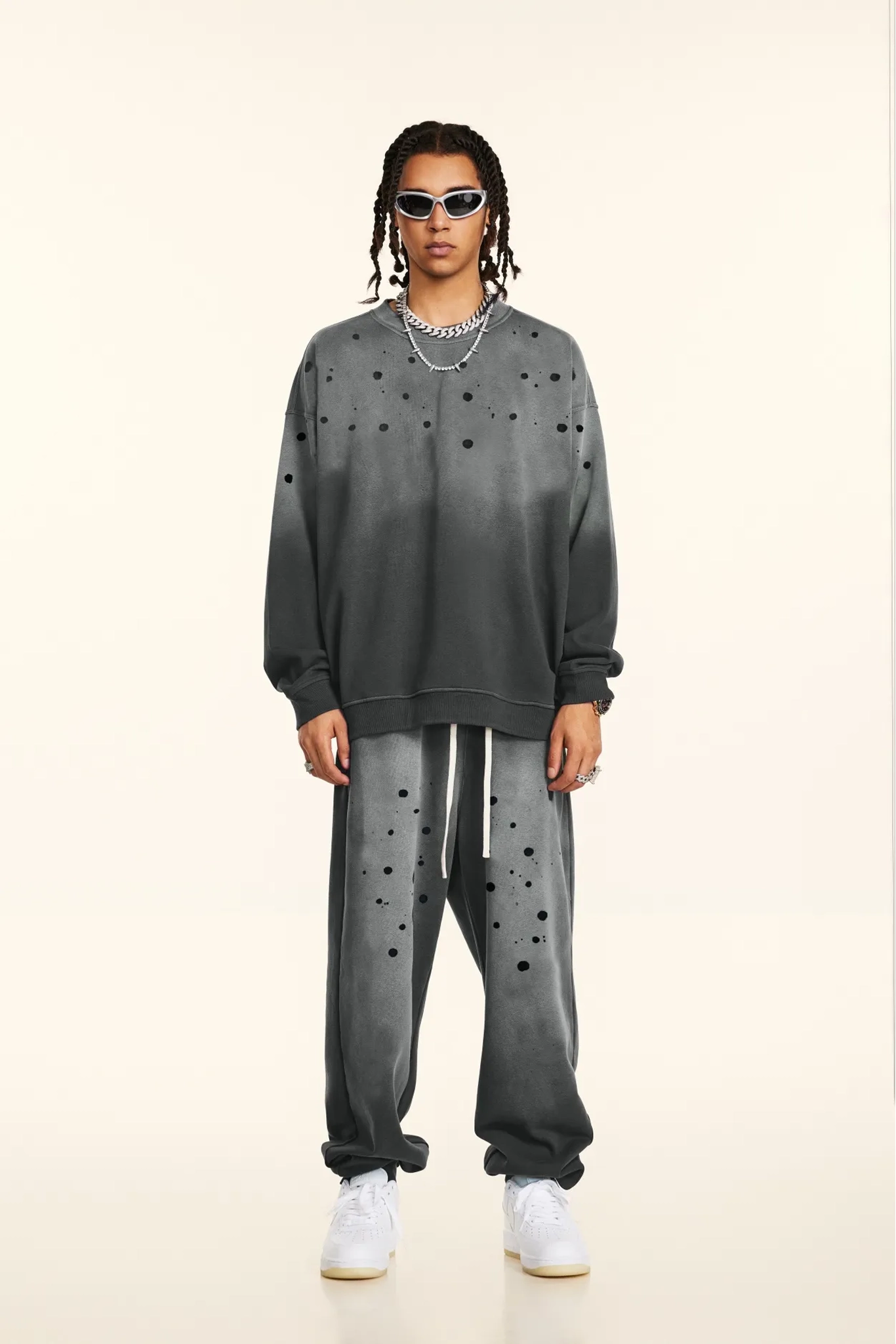 Person wearing a gray sweatshirt and pants with black polka dots on a beige background