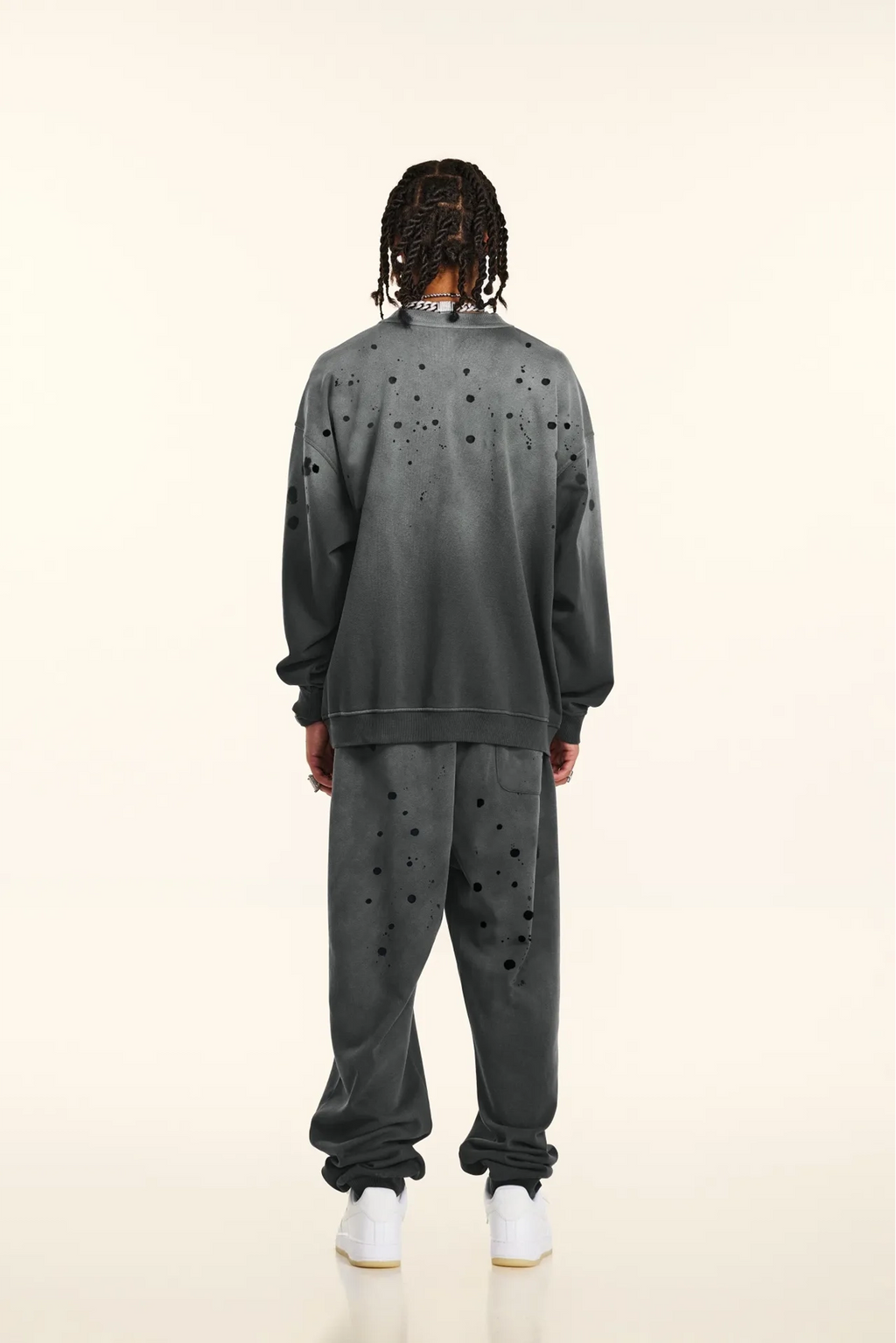 Person wearing a gray distressed sweatshirt and pants on a white background