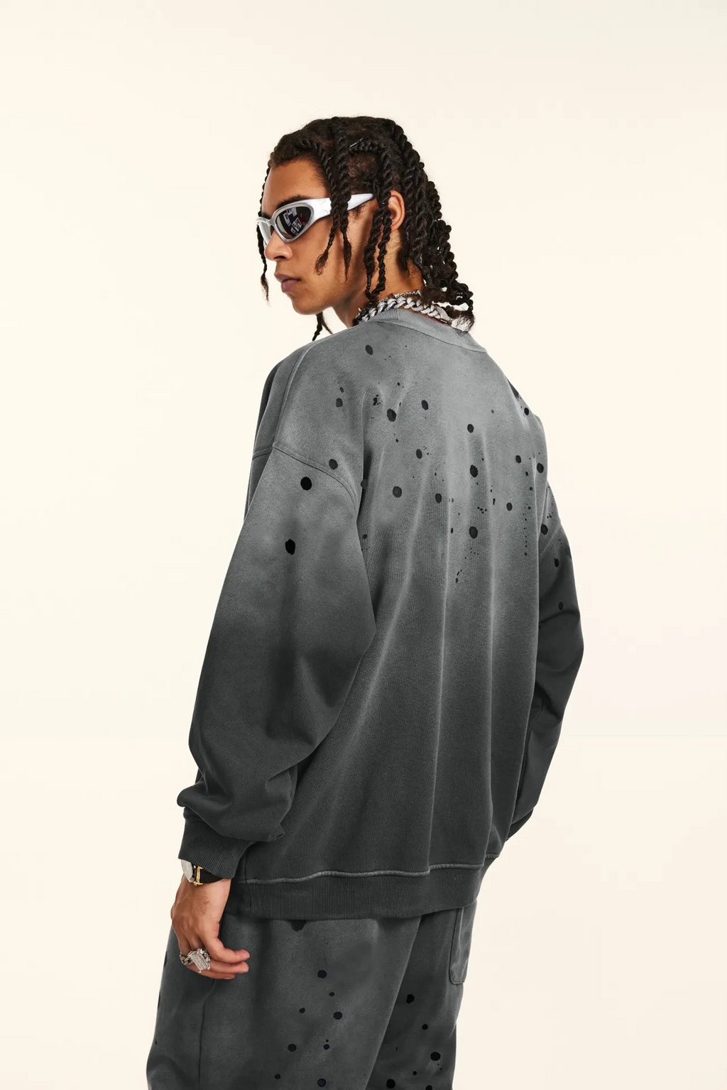 Person wearing a gray sweatshirt with black polka dots on a white background