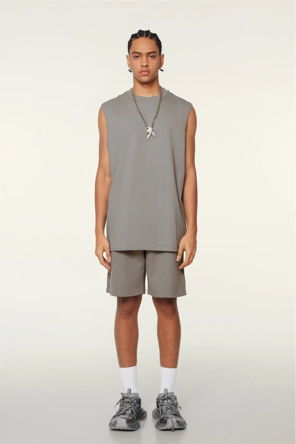 Person wearing a gray sleeveless top and shorts set on a white background