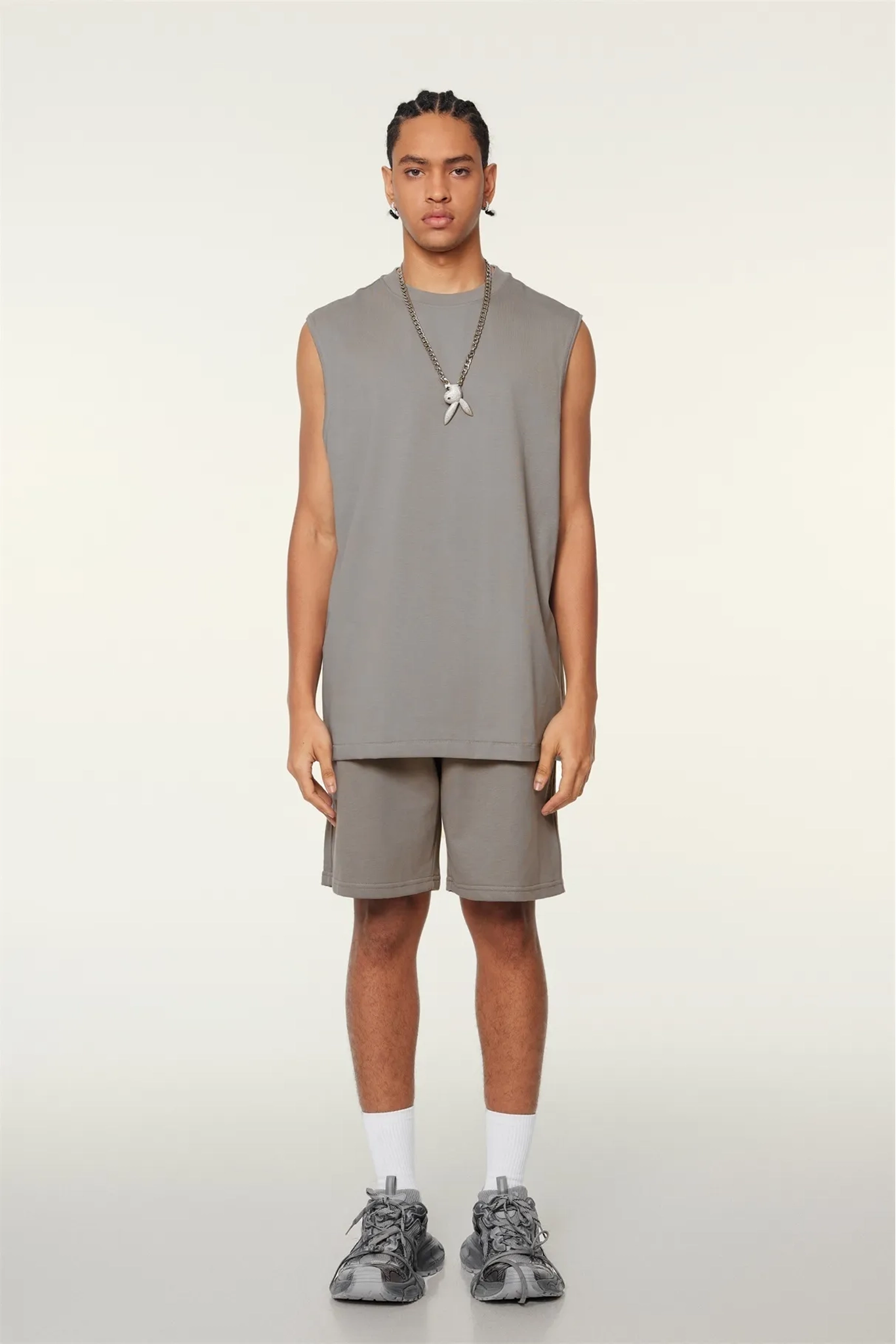 Person wearing a gray sleeveless top and shorts set on a white background