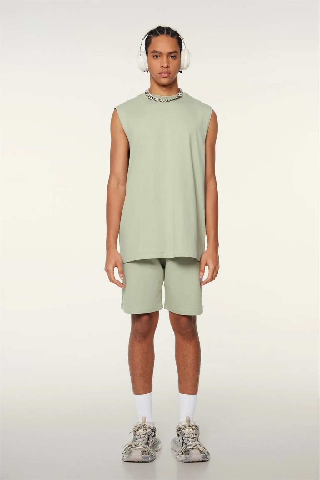 Person wearing a light green sleeveless top and shorts set on a white background