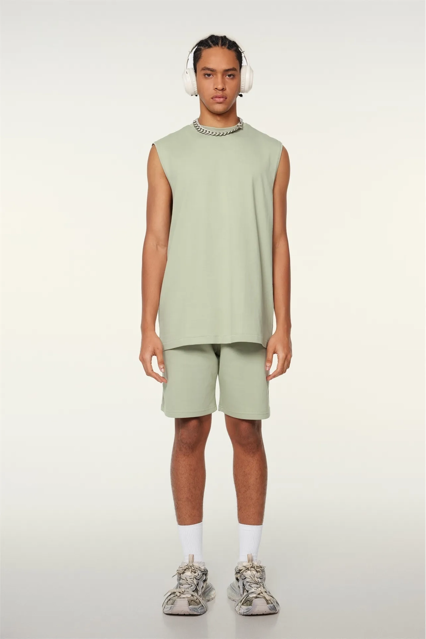 Person wearing a light green sleeveless top and shorts set on a white background