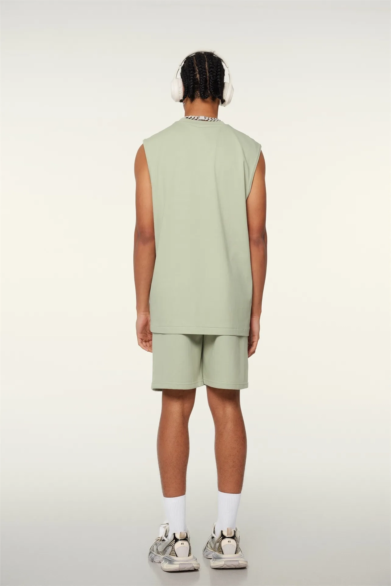 Person wearing a light green sleeveless top and shorts set on a white background