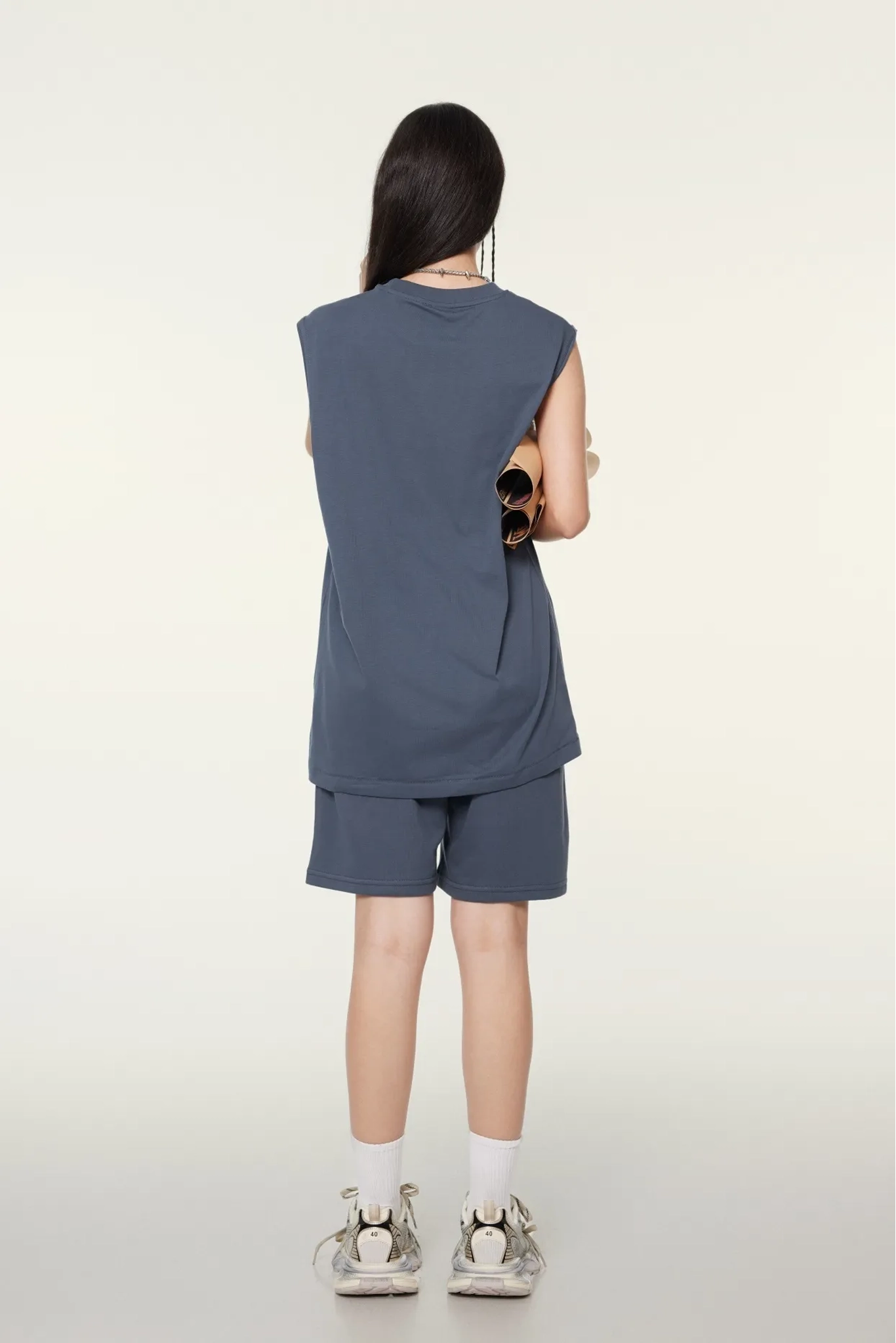 Person wearing a sleeveless top and shorts set on a white background