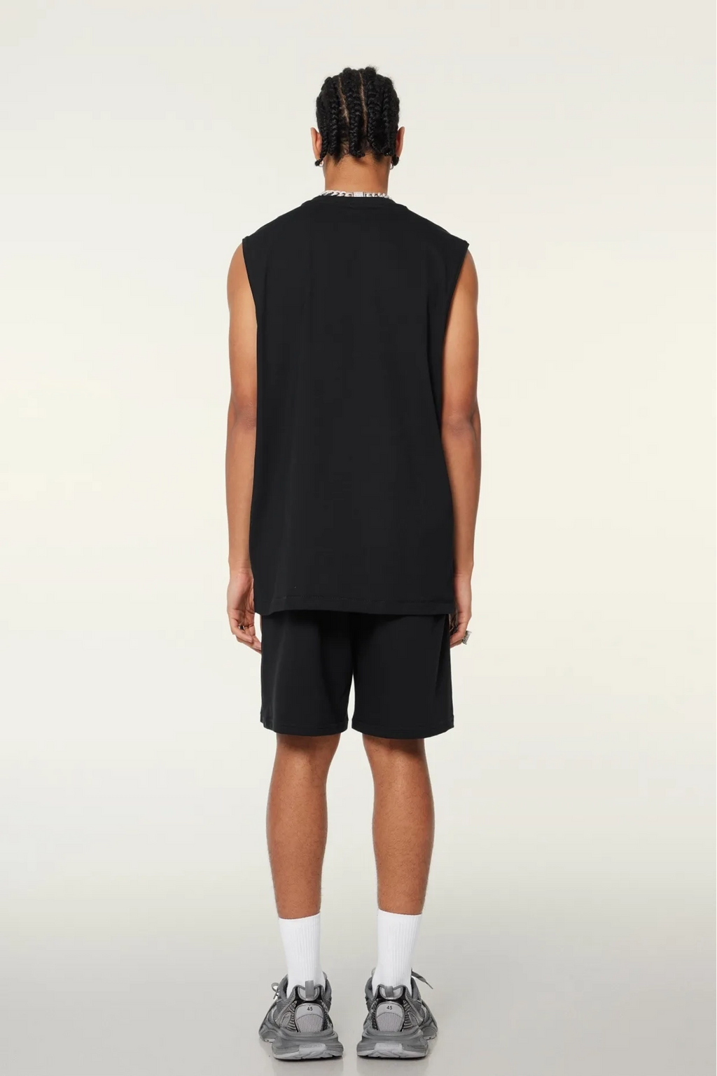 Person wearing a black sleeveless shirt and shorts on a white background