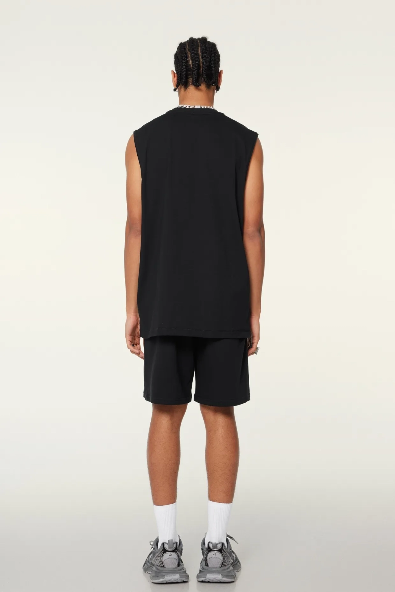 Person wearing a black sleeveless shirt and shorts on a white background