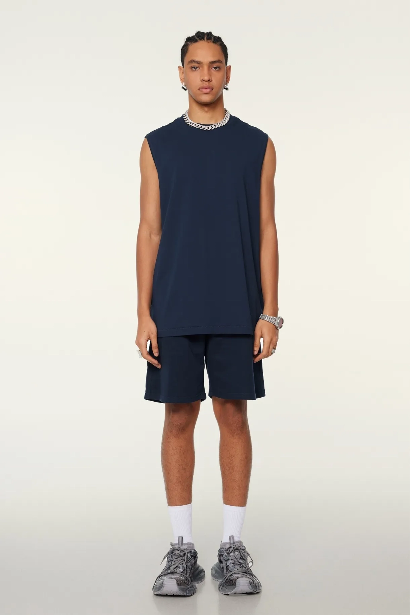 Person wearing a navy sleeveless top and shorts set on a white background