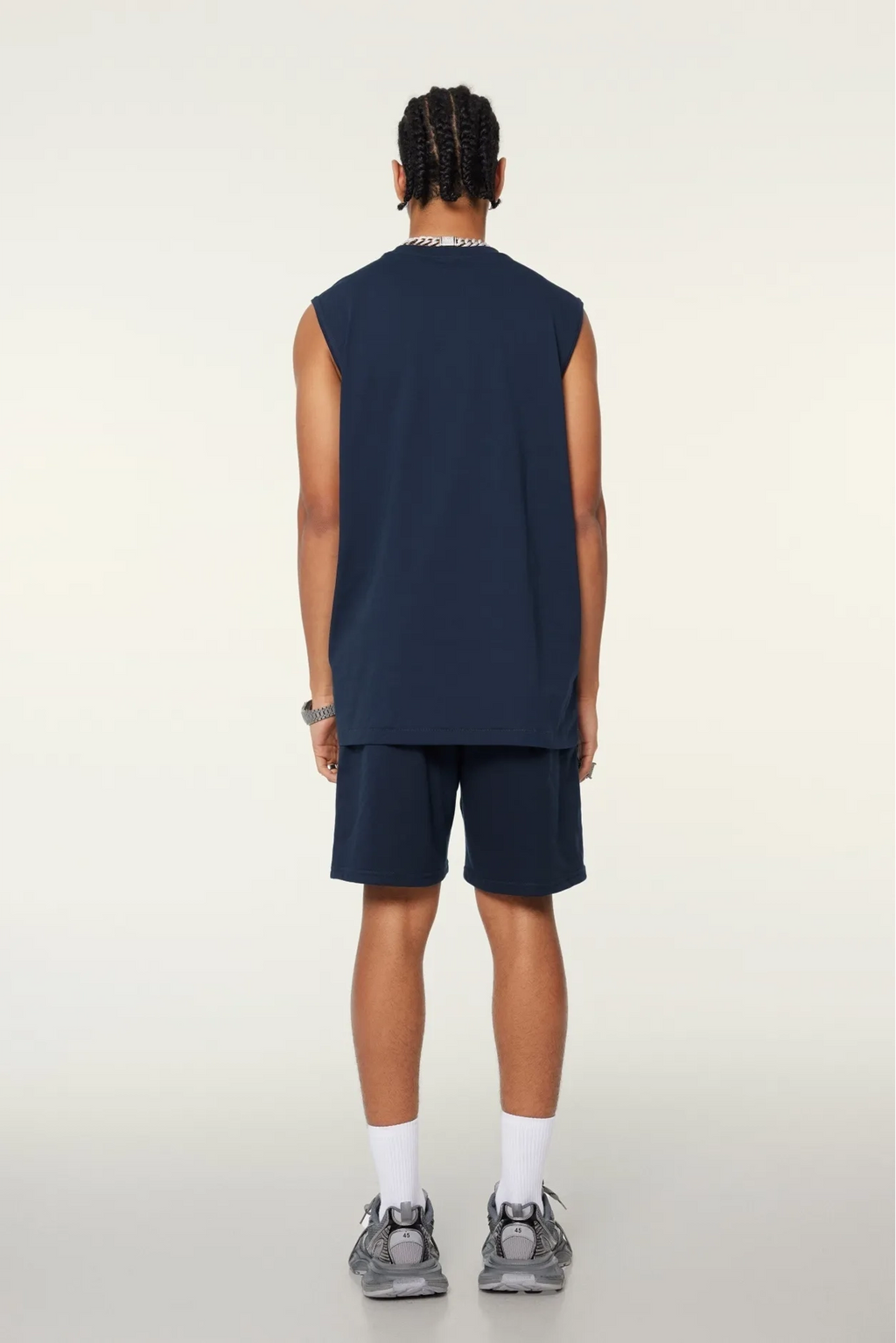 Person wearing a navy sleeveless shirt and shorts on a white background