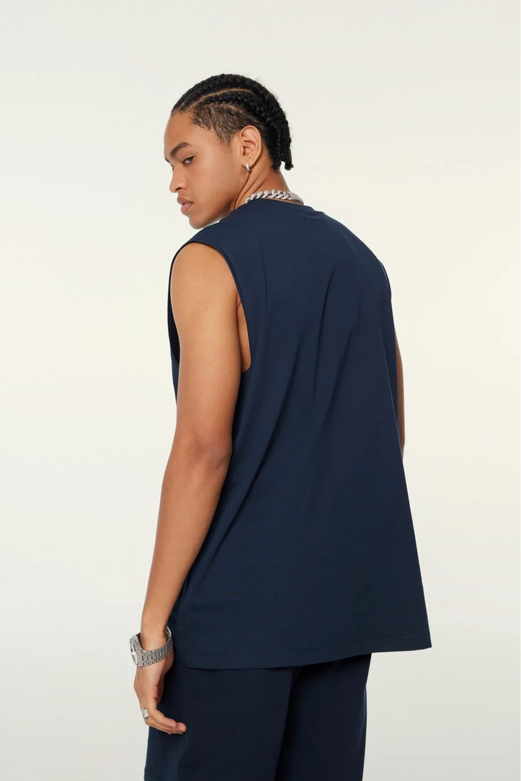 Person wearing a navy sleeveless top and pants on a white background