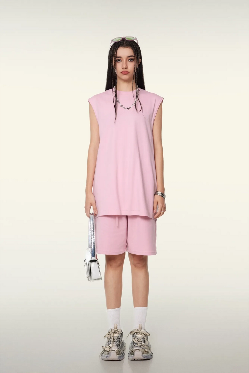 Person wearing a pink sleeveless top and shorts set on a white background