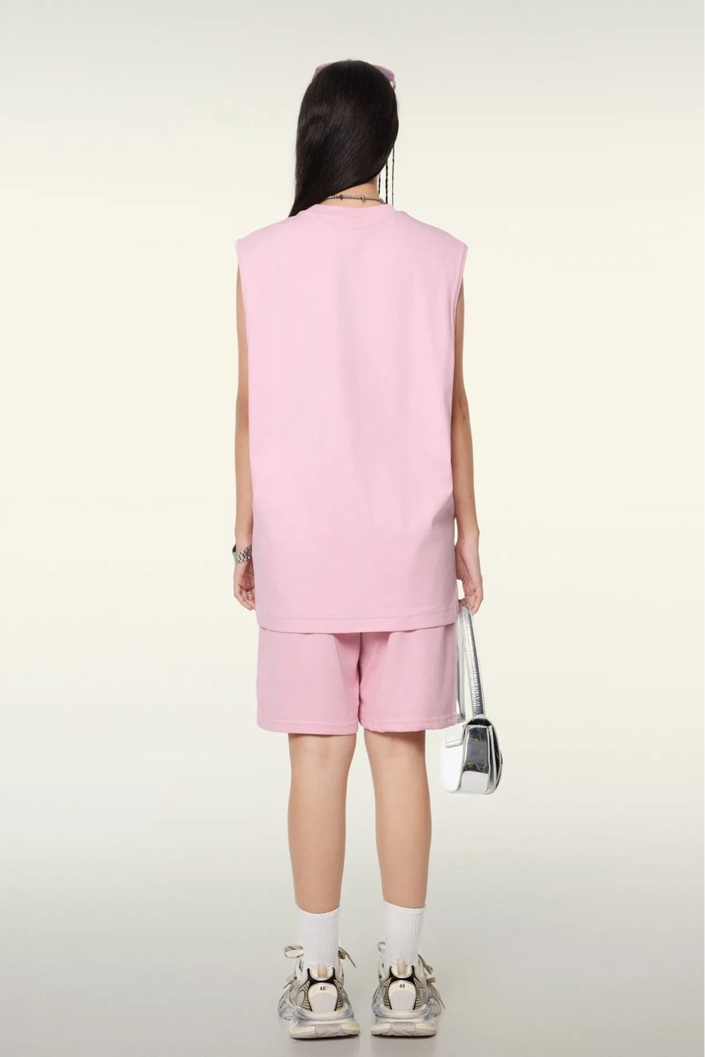 Person wearing a pink sleeveless top and shorts set on a white background