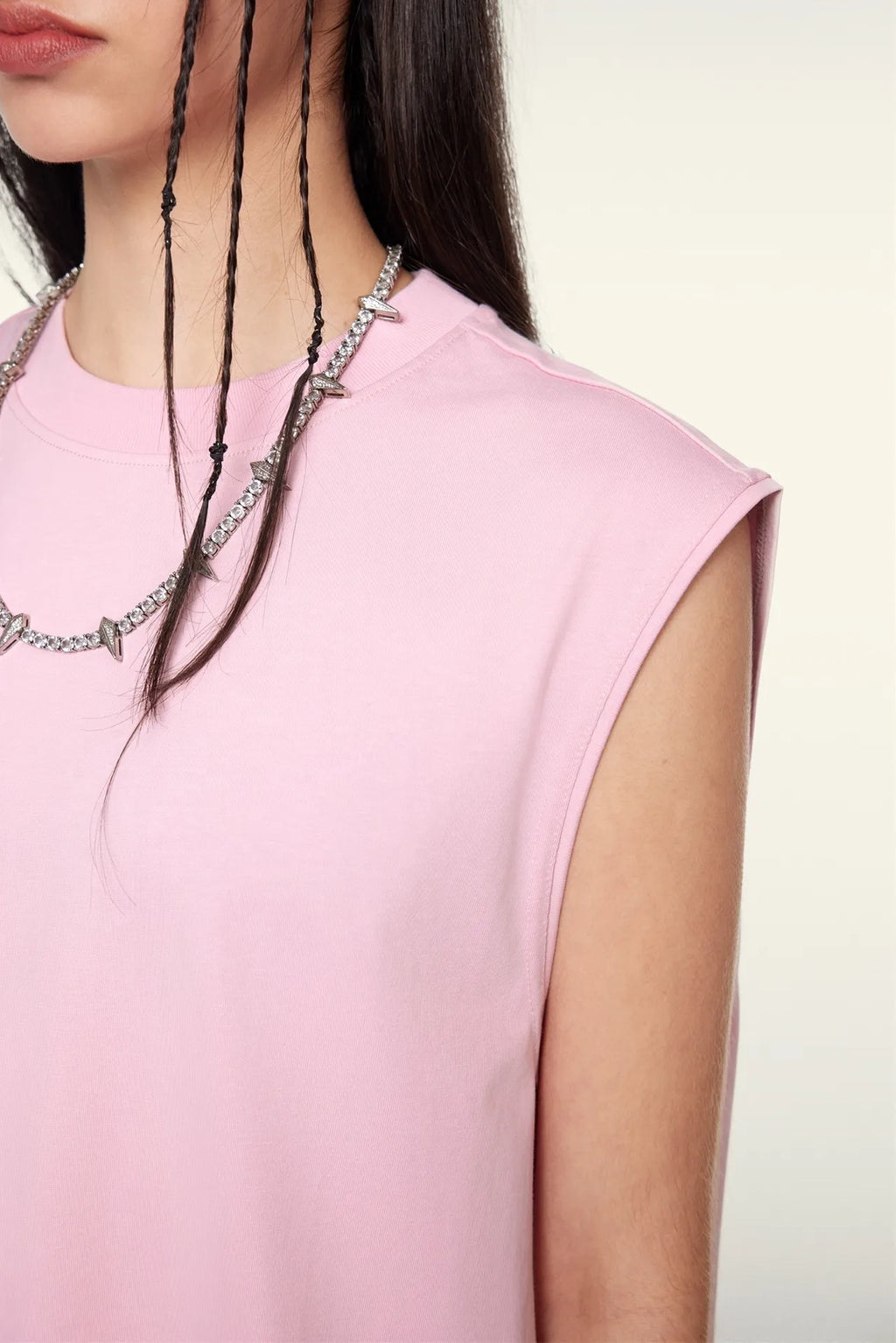 Person wearing a pink sleeveless top with a neutral background