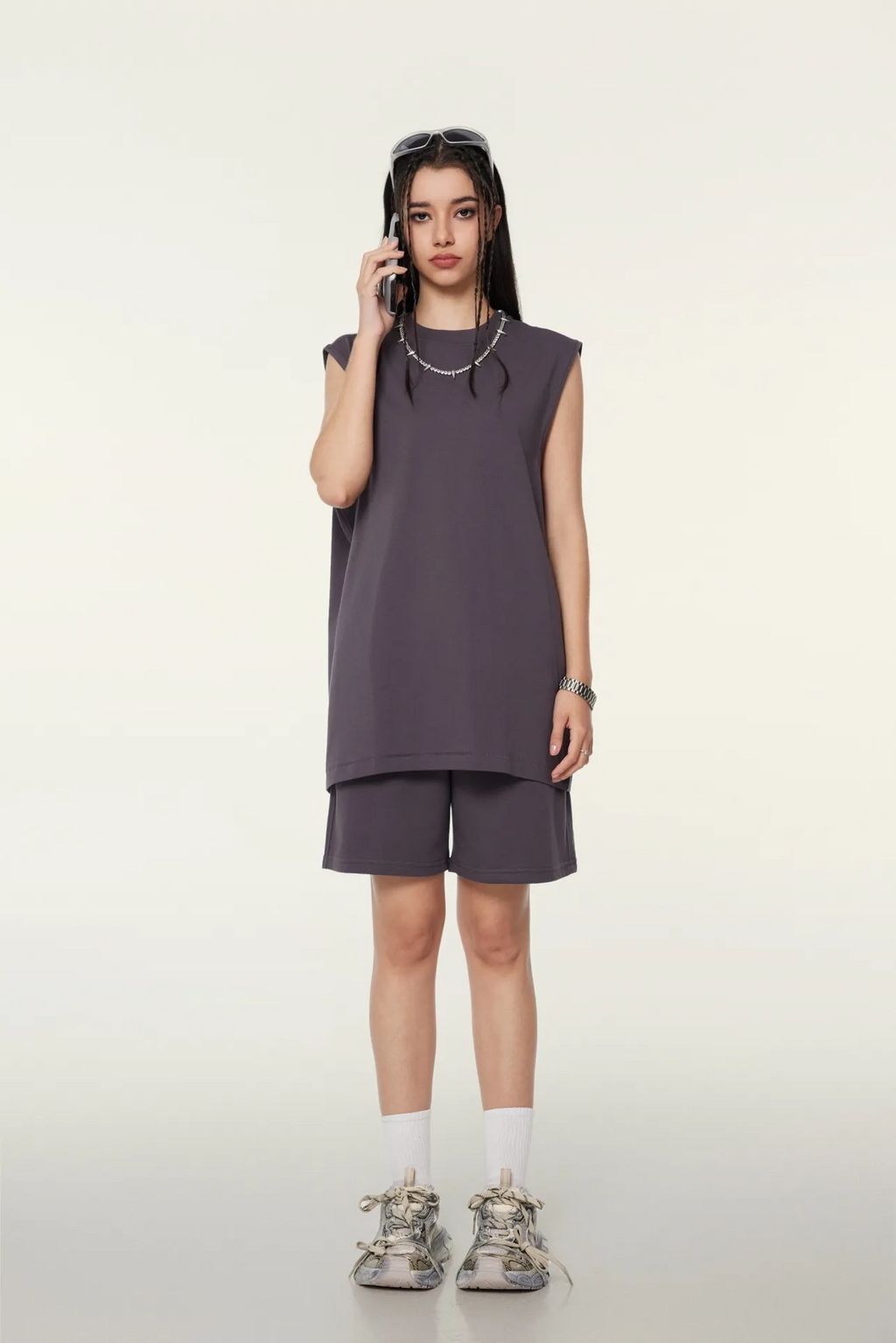 Person wearing a sleeveless gray dress with shorts on a white background