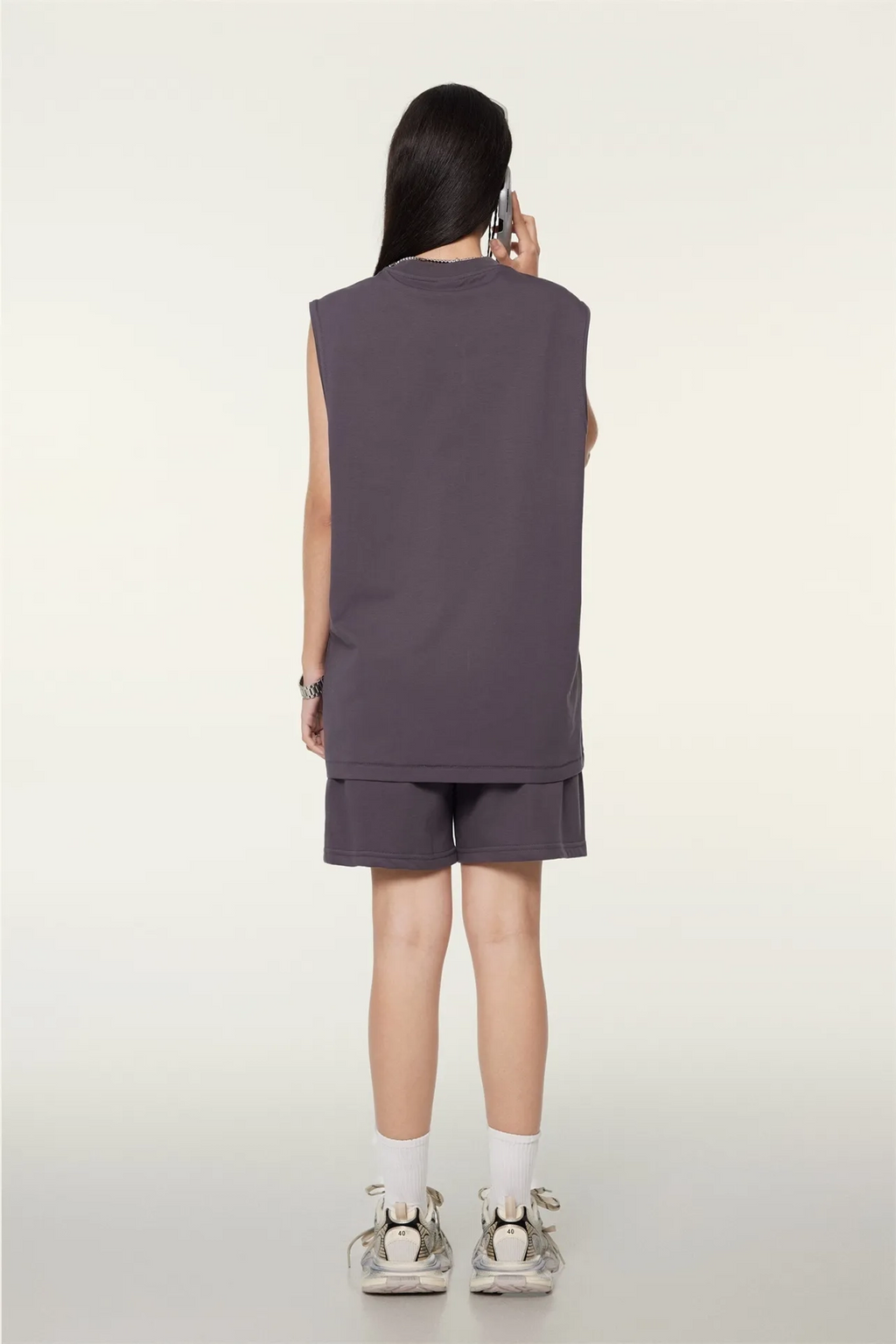 Person wearing a sleeveless top and shorts on a white background