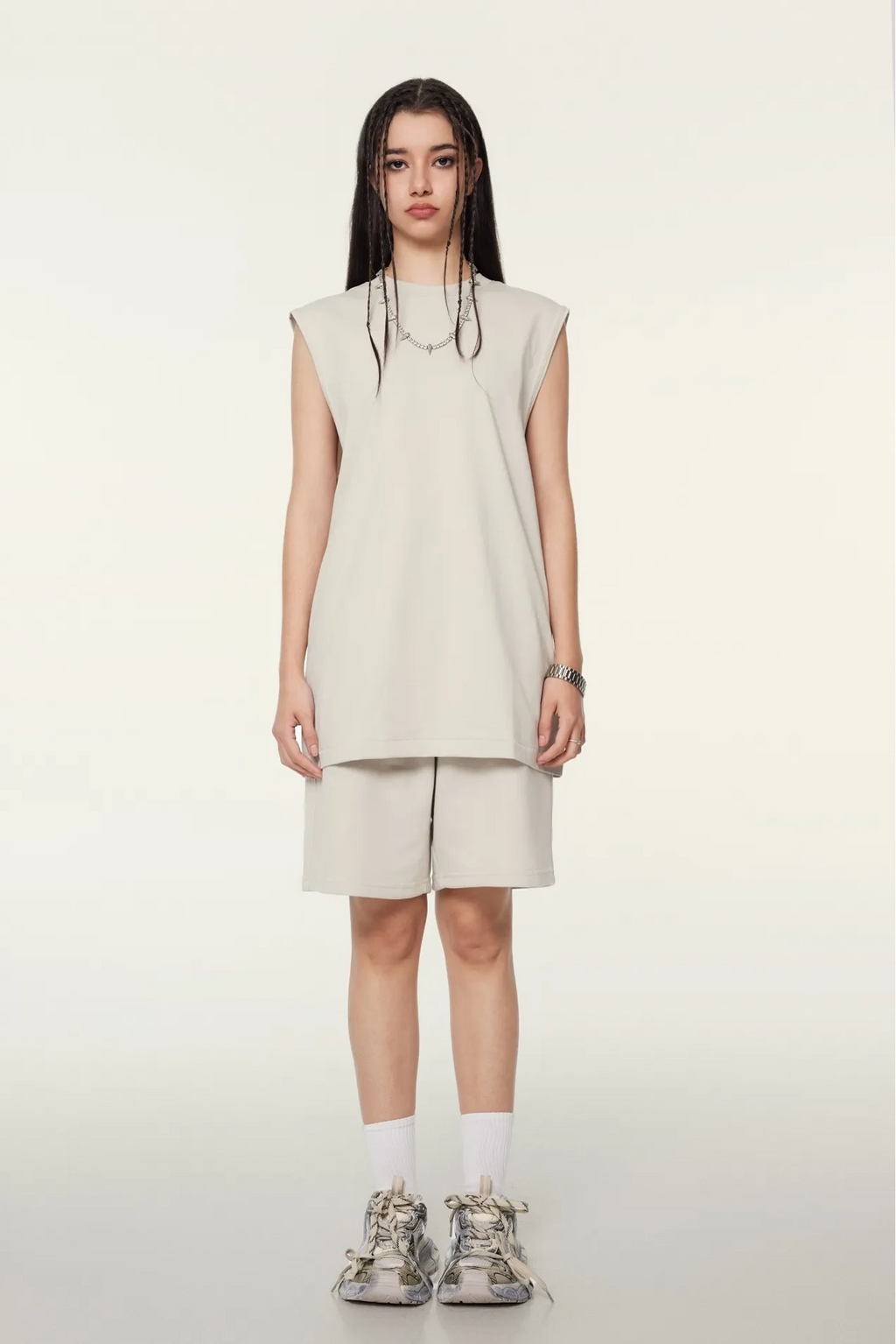 Person wearing a beige sleeveless dress and shorts set on a white background