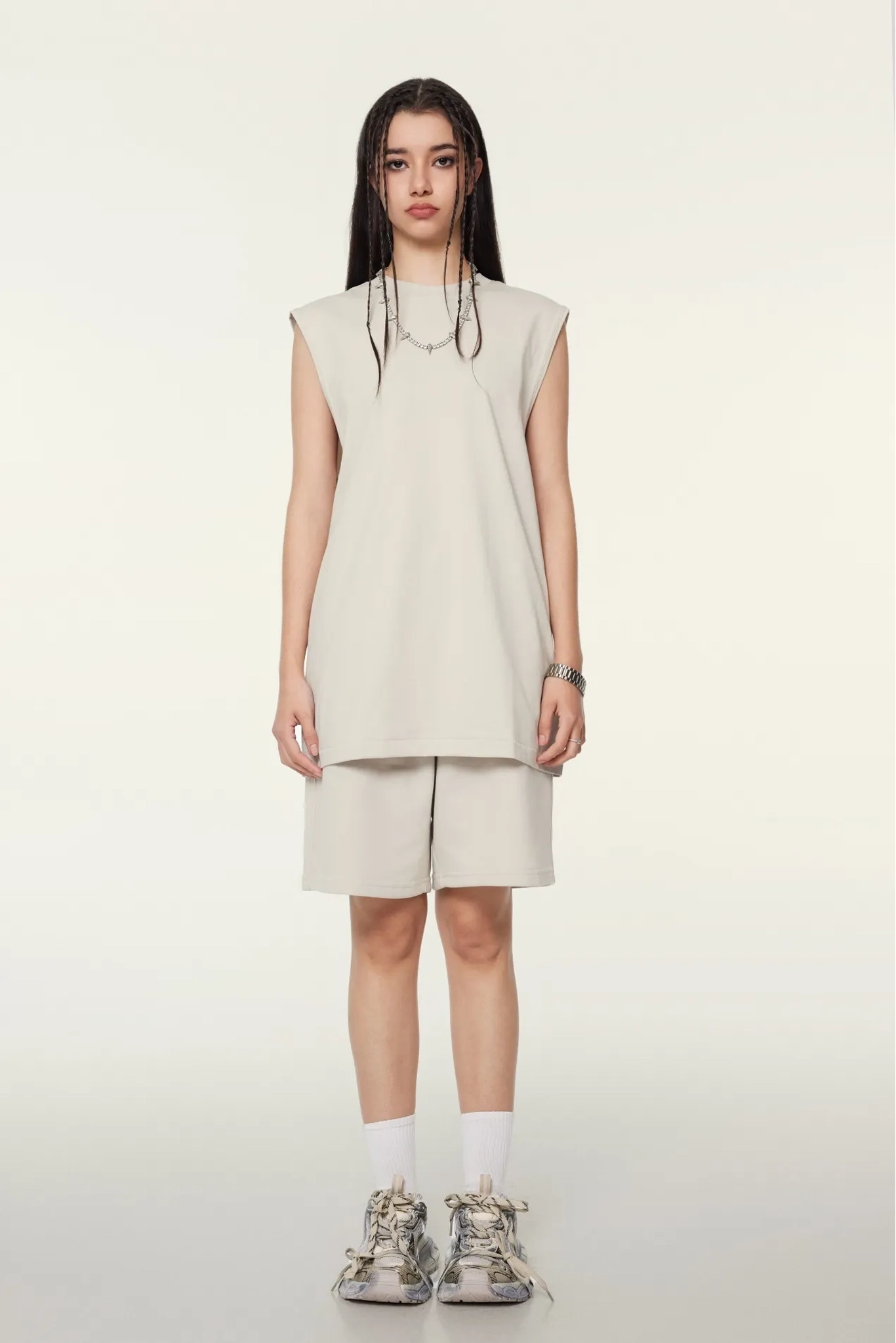 Person wearing a beige sleeveless dress and shorts set on a white background