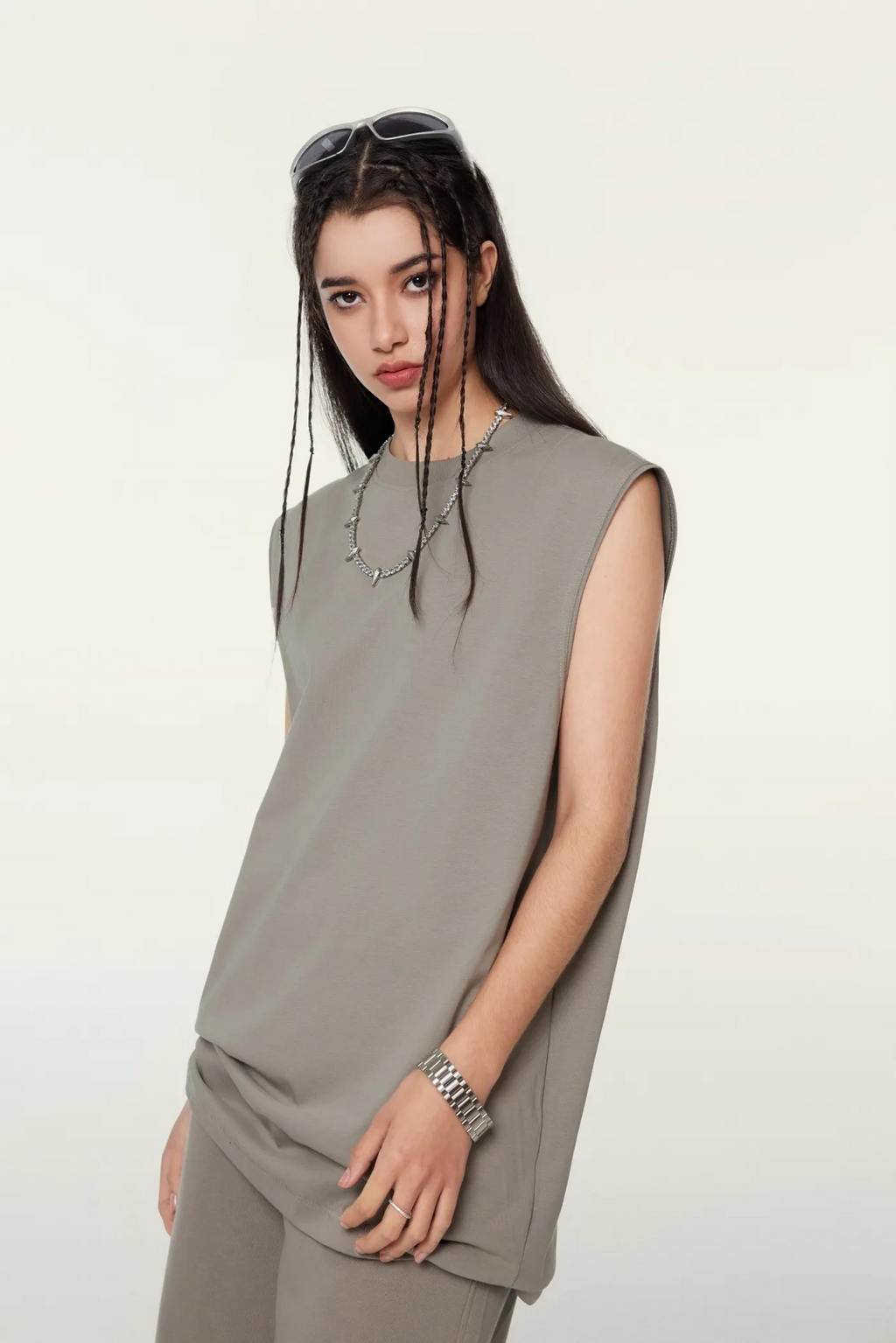 Woman wearing a sleeveless gray top and pants against a white background