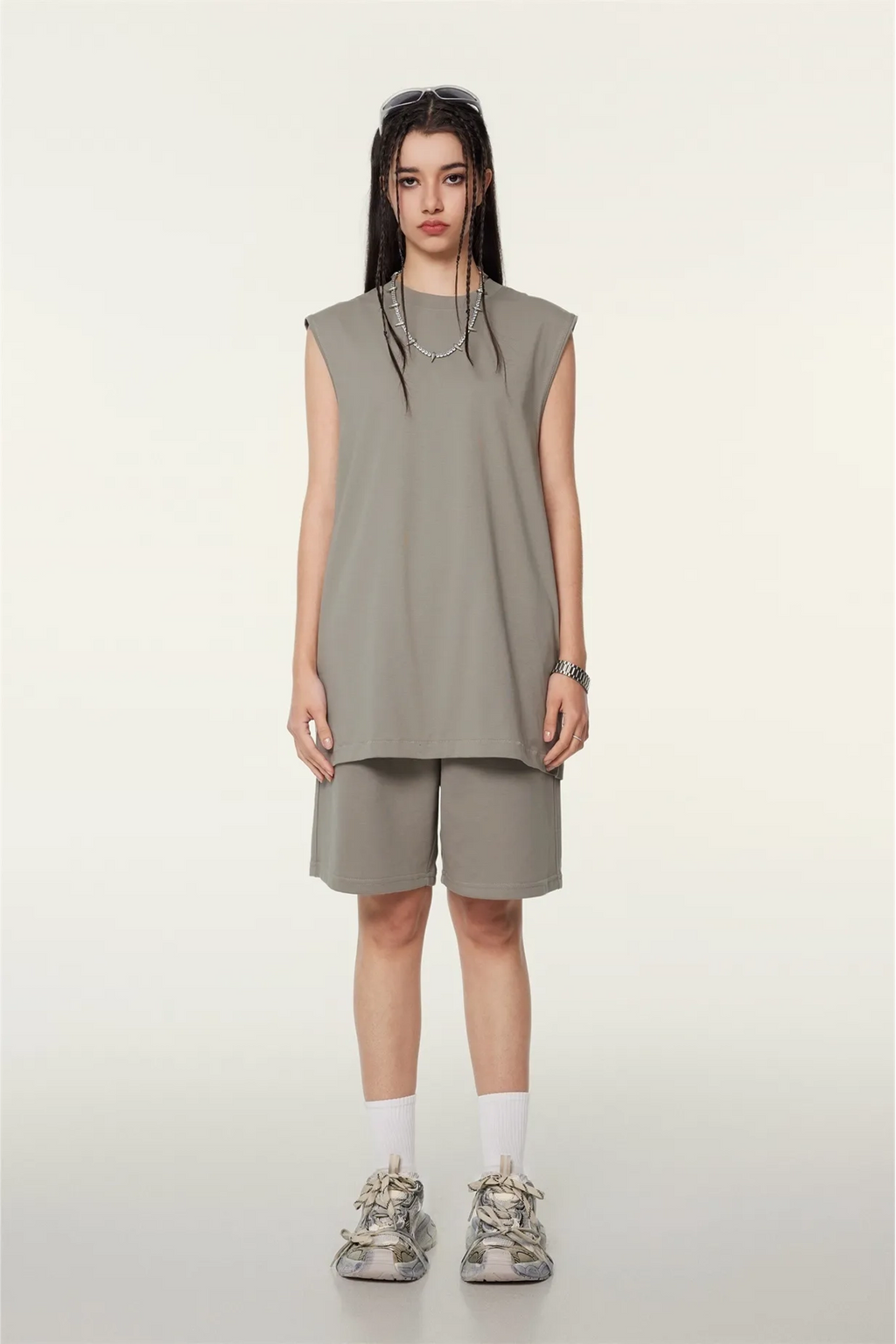 Person wearing a sleeveless beige top and shorts on a white background