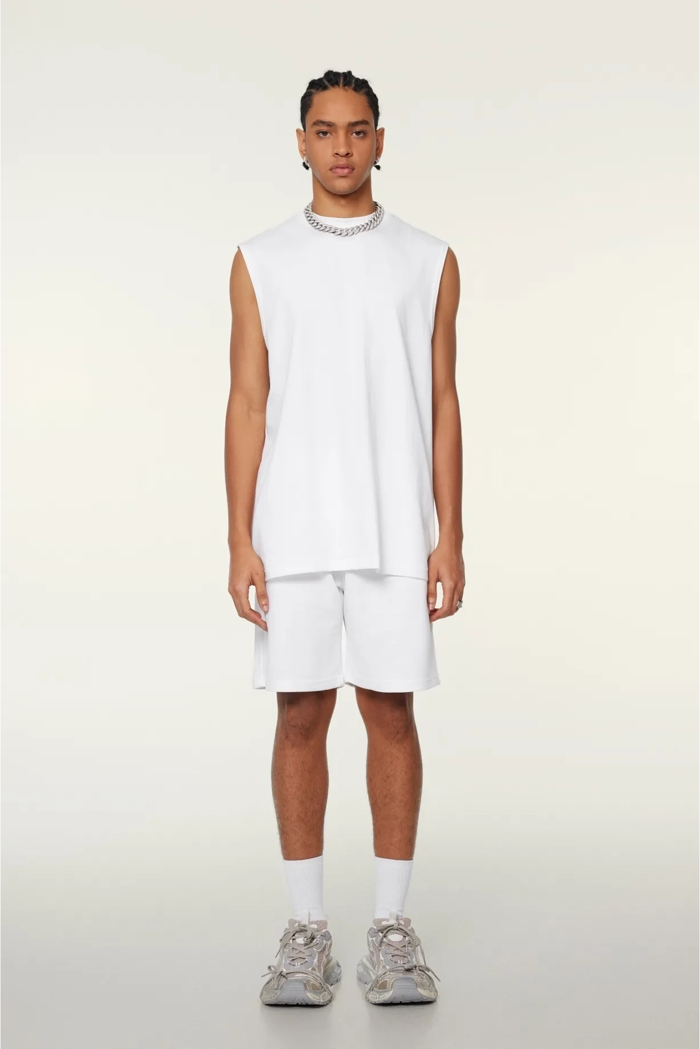 Person wearing a white sleeveless shirt and shorts on a light gray background