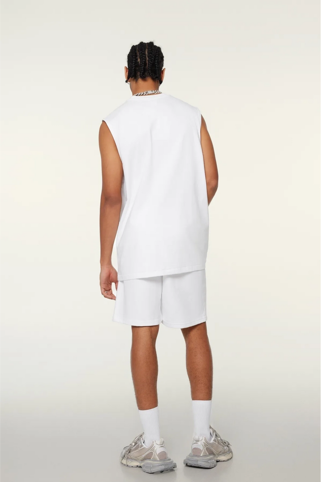 Person wearing a white sleeveless top and shorts set on a plain background