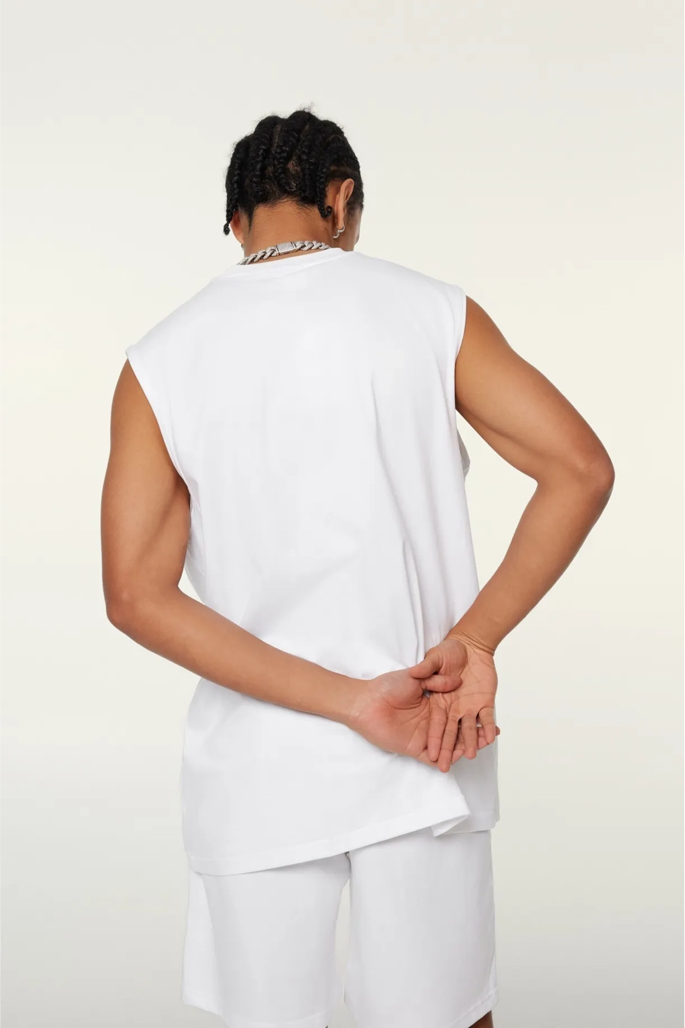 Person wearing a white sleeveless top and pants on a plain background