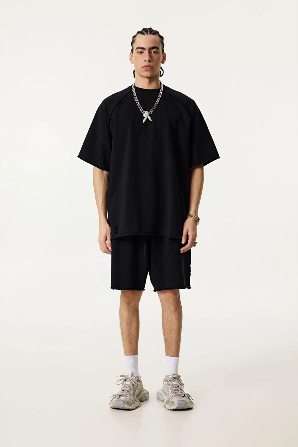 Person wearing an oversized black t-shirt and shorts set on a white background