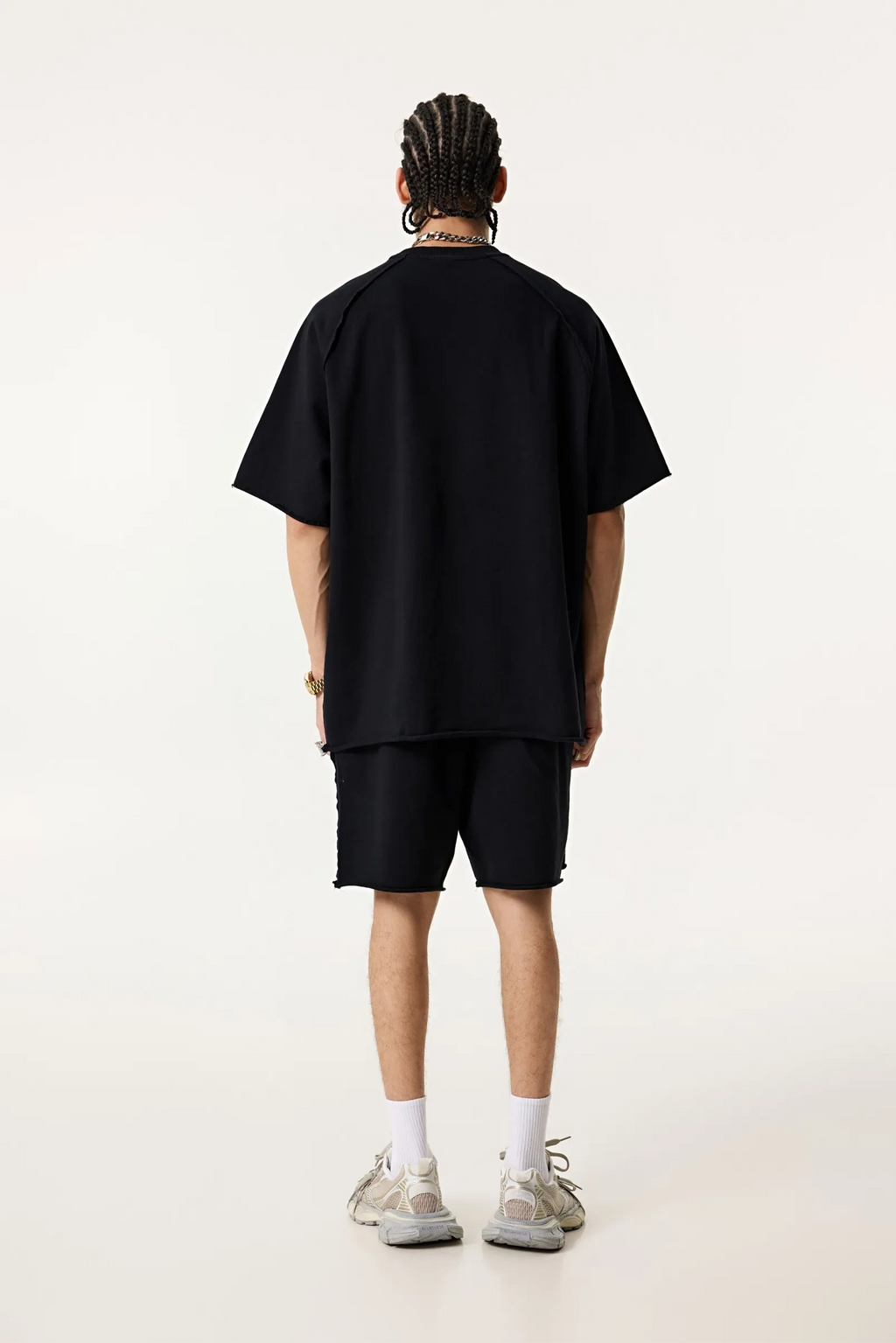 Person wearing a black oversized t-shirt and shorts set on a white background