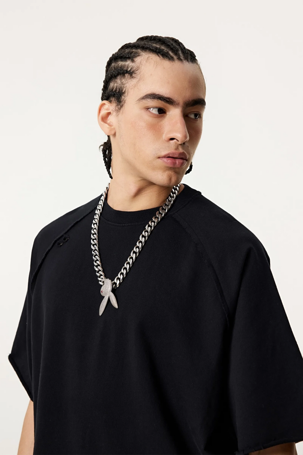 Man wearing a black oversized shirt and a large chain necklace with a pendant on a white background