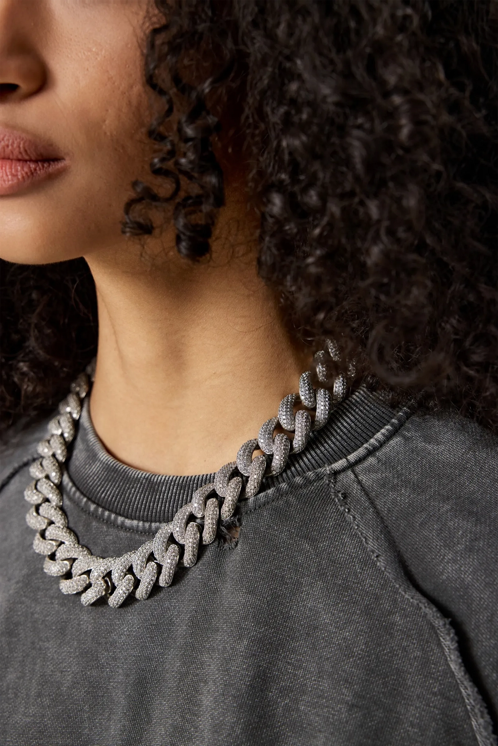 Close-up of a person wearing a silver chain necklace on a gray background