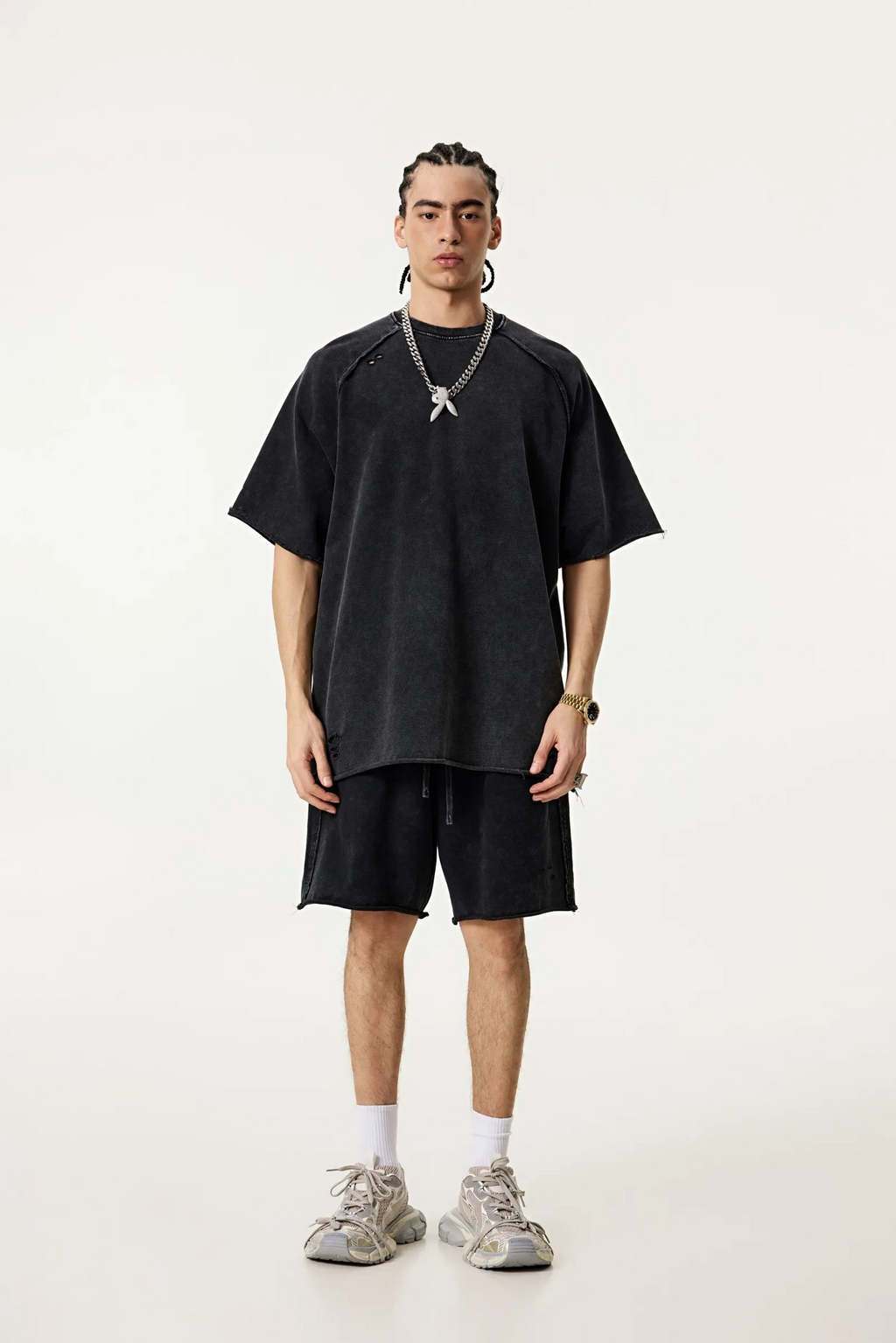 Person wearing a black oversized t-shirt and shorts set on a white background