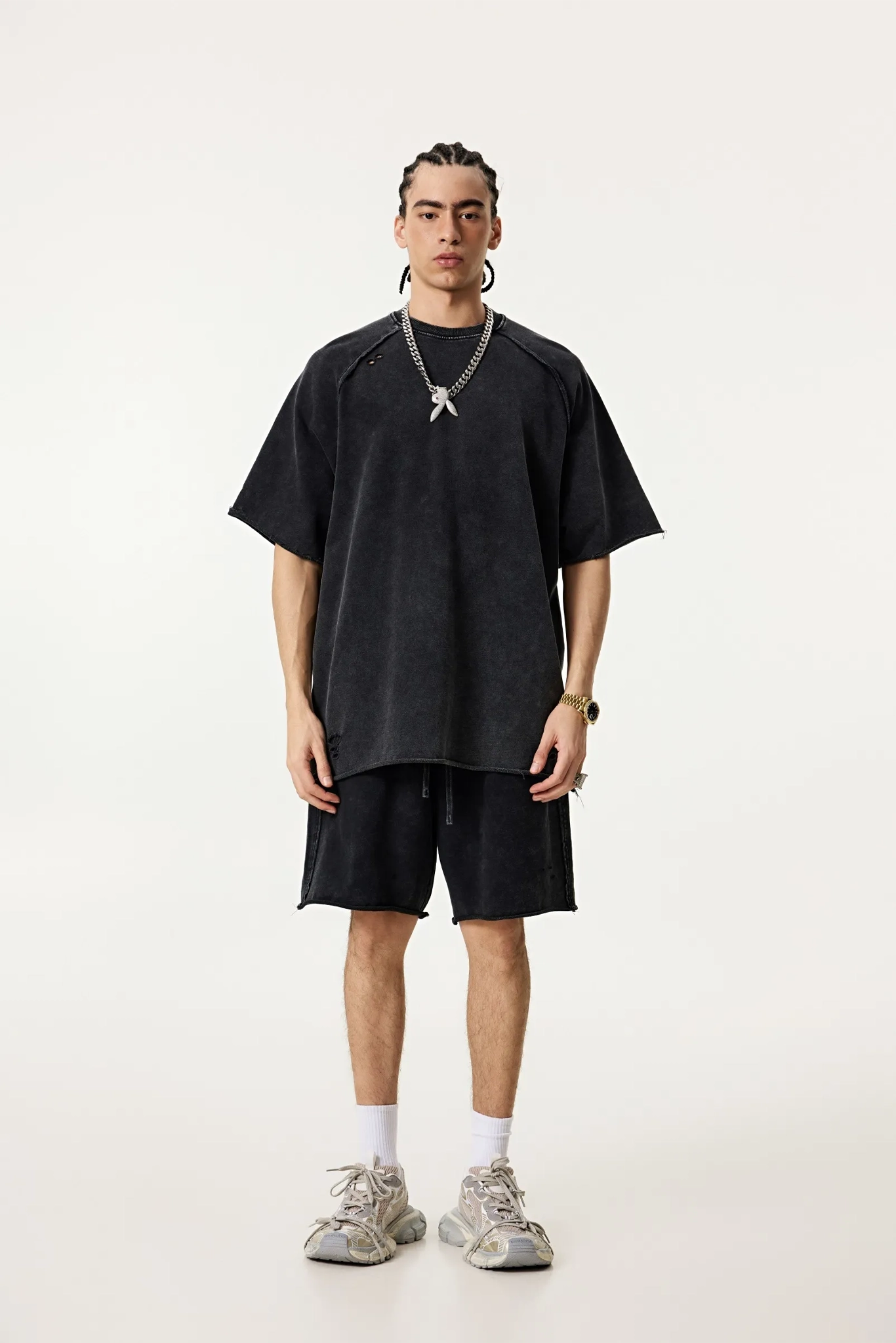 Person wearing a black oversized t-shirt and shorts set on a white background