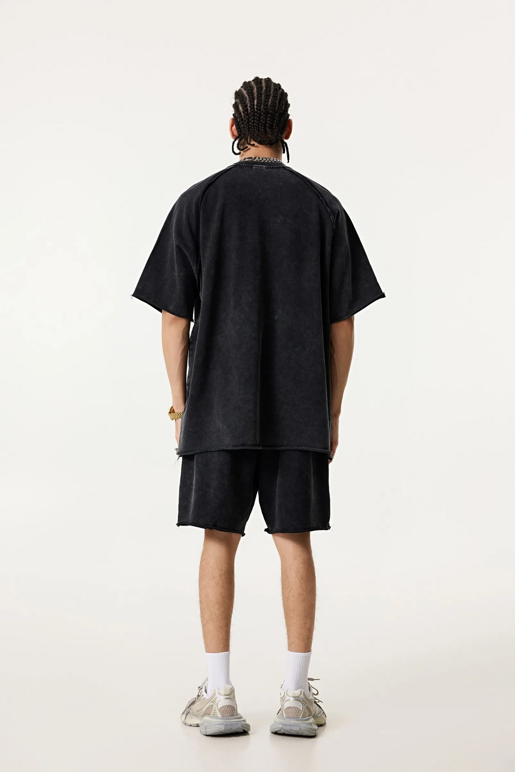Person wearing a black oversized t-shirt and shorts set on a white background