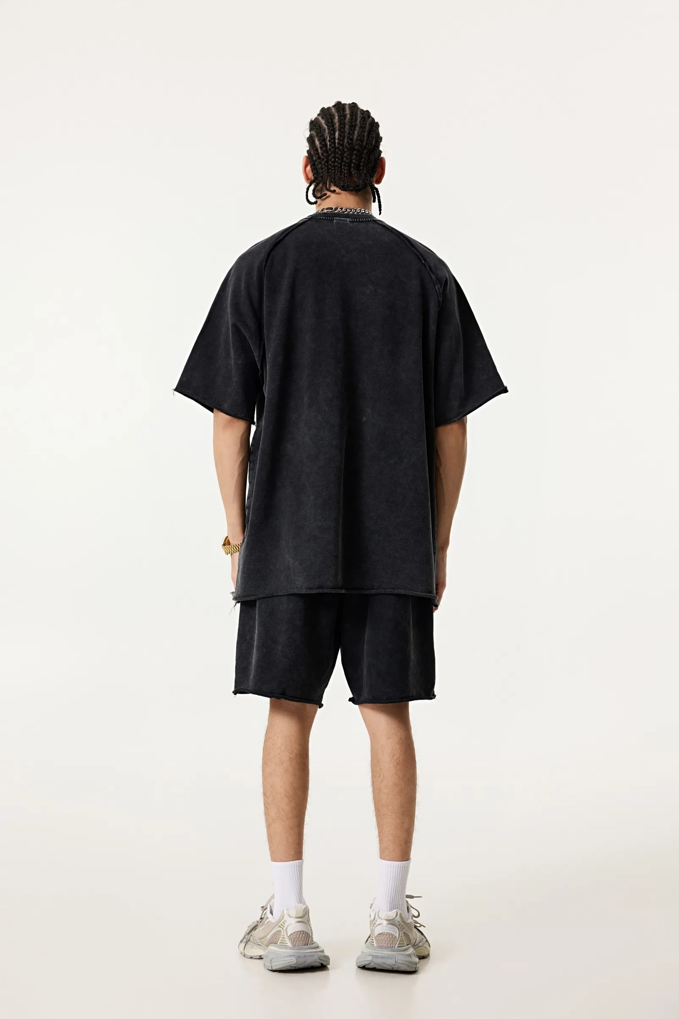 Person wearing a black oversized t-shirt and shorts set on a white background