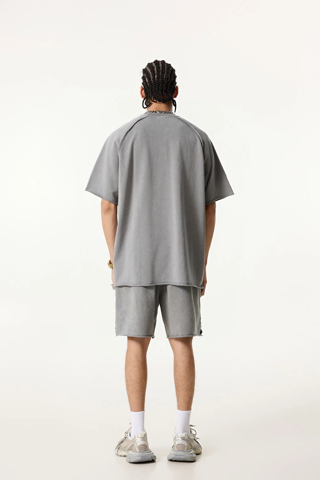 Person wearing a gray oversized t-shirt and shorts set on a white background