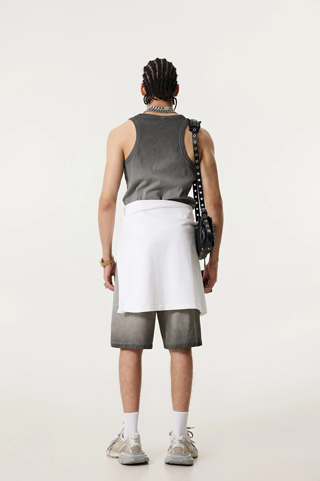 Person wearing a gray sleeveless top, white skirt, and shorts on a plain background